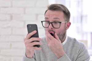 uomo stupito con smartphone in mano