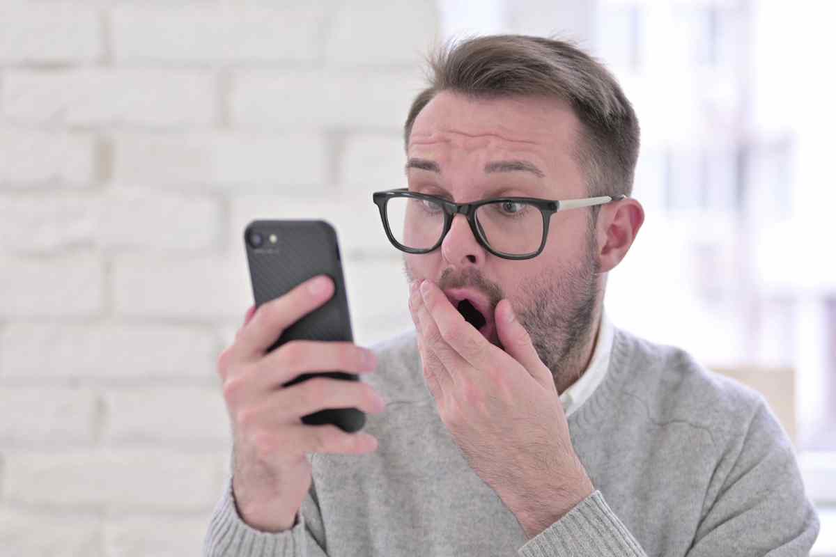 uomo stupito con smartphone in mano